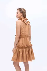 Vestido corto de lino color beige, con cuello alto fruncido, sin mangas y diseño en capas con volados.