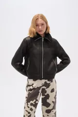 Campera corta negra de cuero sintético con cuello y puños de piel sintética negra, cierre frontal con cremallera y bolsillos laterales con cremallera.