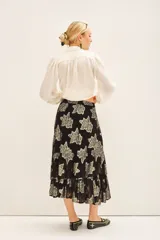 Falda larga de tiro alto con calce amplio, confeccionada en viscosa jacquard con detalles de lurex dorado. Presenta cintura elastizada con cordón de ajuste y volados irregulares en el ruedo. Incluye forrería a tono.