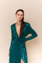 Vestido largo de lentejuelas color negro, con escote profundo en V, mangas largas y tajo lateral en la falda. Presenta un diseño cruzado con fruncido en la cintura y espalda elastizada.