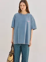 Remera oversize celeste con efecto lavado, cuello redondo, mangas cortas y pequeño gráfico frontal en tono rosado.