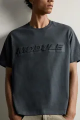 Camiseta relaxed fit de manga corta y cuello redondo, color gris oscuro, con estampado en relieve tono sobre tono con la palabra 'MODULE' en el frente.