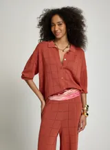 Camisa de punto de algodón color terracota con diseño a cuadros texturizados, cuello solapa, cierre frontal de botones y mangas cortas.