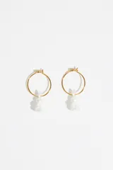 Aros de aro pequeño en color dorado con un dije colgante en forma de conejo de color blanco con acabado flocado.