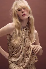 Top de cuello halter con diseño sin mangas, confeccionado en tela fluida con estampado de manchas abstractas. Presenta un cierre en la espalda con abertura y botones.