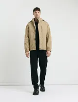 Campera 2 en 1 color beige, con cuerpo y capucha desmontable, manga larga, cierre frontal con botones a presión y bolsillos laterales engomados.