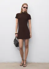 Vestido corto de tejido de punto fino color marrón, con cuello perkins y mangas cortas. Presenta un diseño evasé que se ajusta suavemente al cuerpo.