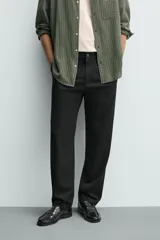 Pantalón de corte recto confeccionado en tejido elástico, con cintura elástica, pliegues frontales, bolsillos laterales y bolsillos traseros de vivo con botón.