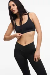 Top deportivo de microfibra en color beige con detalles de ribetes y banda inferior en color marrón. Presenta diseño de espalda estilo nadadora y logo de la marca estampado en la banda elástica inferior.