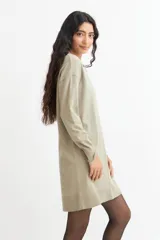 Vestido tipo sweater color blanco, de corte recto y largo hasta la rodilla, con cuello redondo y mangas largas.