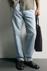 Jeans regular fit confeccionados en denim de algodón celeste con efecto lavado, de cinco bolsillos y cierre frontal con cremallera y botón.