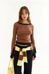 Top de manga larga con diseño de doble capa superpuesta, combinando una capa superior negra y una inferior marrón. Presenta cuello redondo, ajuste al cuerpo y detalle de bordado BG en la parte inferior.