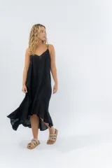 Vestido negro midi con tirantes finos y escote en V. Diseño fluido con bajo asimétrico.