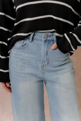 Jean wide leg de tiro alto en denim color celeste claro. Presenta un diseño de cinco bolsillos, destacándose los bolsillos traseros con solapa y detalle de marca metálica. Posee cierre frontal con botón y ruedo recto.