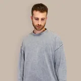 Buzo gris de corte oversize con efecto acid wash, cuello redondo y puños y cintura acanalados.