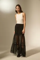 Falda larga de color negro, confeccionada en tela semitransparente con detalles de encaje en los niveles de la falda y cintura elástica.