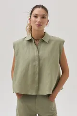 Blusa verde militar sin mangas, confeccionada en lino, con cuello camisero, cierre frontal con botones y corte holgado.