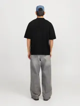 Polo de tejido estructurado negro, con hombros caídos, ajuste holgado, cuello tipo polo, mangas cortas y cierre frontal con botones.