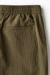 Pantalón corto de tejido texturizado verde militar, con corte relajado, cintura elástica con cordón de ajuste y bolsillos laterales.