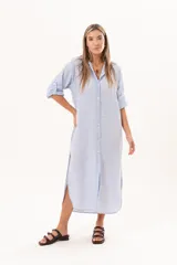Vestido camisero largo color celeste, de silueta relajada con abotonadura frontal completa, cuello camisero y mangas regulables. Presenta tajos laterales y detalle de bordado sutil en la manga.