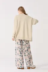 Cardigan color beige con lurex, escote en V, manga larga, botones de pasta, bolsillos delanteros y terminaciones de rib.