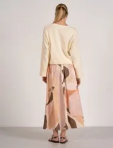 Falda larga de tiro alto con cintura elastizada y bolsillos laterales, con diseño estampado de formas abstractas en tonos cálidos y neutros.