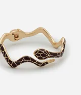 Pulsera rígida con forma de serpiente esmaltada en tonos marrones y detalles en blanco y dorado.