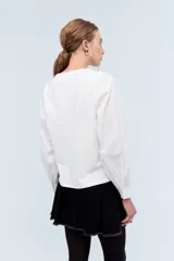 Blusa blanca de algodón con escote en V y mangas largas abullonadas.