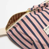 Riñonera de tela con estampado de rayas azules y rosadas, cierre superior con cremallera dorada y correa ajustable color beige. Incluye etiqueta frontal con la inscripción "GET IT.".