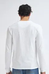 Remera manga larga de algodón en color blanco, con cuello redondo y tapeta frontal con tres botones.