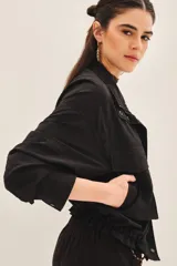 Campera negra de estilo militar o utilitario, con cuello alto, bolsillos delanteros con tapa y cordón ajustable en el ruedo.