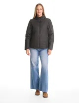 Campera 3 en 1 de color beige, con sistema de capas desmontables. La capa exterior es de tejido técnico resistente al viento y lluvia ligera, con capucha fija, cierre frontal con solapa, bolsillos de parche y ajuste elástico interno en la cintura. Incluye una campera interior capitoneada ultraliviana que puede usarse de forma independiente.