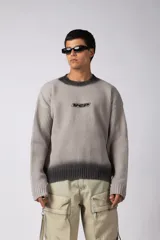 Sweater de punto acanalado con diseño degradado de negro a gris en el cuello y el ruedo. Presenta un corte regular y un pequeño bordado central en el pecho.