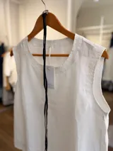 Blusa de lino color beige, sin mangas, con cuello redondo y silueta relajada. Incluye un cinturón fino desmontable de cuero negro.