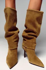 Bota de tacón alto de serraje color camel, con caña alta y diseño de calce fácil. Presenta tacón fino y punta.