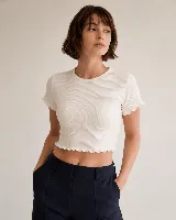 Remera de morley de algodón, color blanco, con cuello redondo, manga corta y terminaciones con borde fruncido en mangas y ruedo.