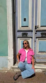 Camisa corta color fucsia, con cuello, cierre frontal de botones y dos bolsillos delanteros con solapa, de manga corta y corte recto.