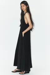 Vestido midi de corte fluido, cuello redondo y diseño sin mangas. Presenta una abertura en la espalda con cierre de lazada ajustable.