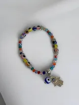 Pulsera elástica compuesta por cuentas de cristal multicolor y abalorios de ojos turcos, con dije colgante de mano de Fátima decorado con cristales y un ojo turco adicional.