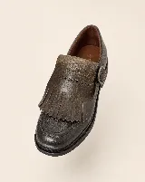 Mocasín de cuero natural color marrón oscuro, con costuras visibles, hebilla lateral metálica y solapa desmontable con flecos.