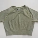 Remera deportiva verde oliva de corte cropped, con cuello redondo y mangas cortas.