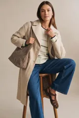 Tapado largo de corte oversize en color beige, con solapas clásicas y cierre frontal con botones. Presenta un diseño minimalista y elegante, ideal para un look sofisticado.