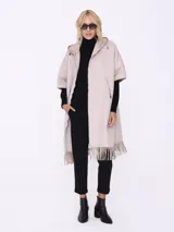 Tapado negro sin mangas con flecos en el ruedo y cierre frontal con cremallera.