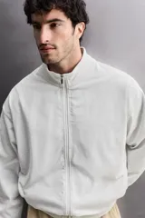 Sudadera de corte relajado con cierre frontal de cremallera, confeccionada en tejido ligero de mezcla de algodón. Presenta cuello subido, manga larga, bolsillos laterales ocultos en costura y acabados en rib.