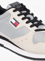 Zapatillas runner Tommy Jeans Eva de estilo urbano, confeccionadas con una combinación de textil, cuero y material sintético en tonos gris, beige y negro. Cuentan con cordones negros, suela bicolor y detalles de la marca.