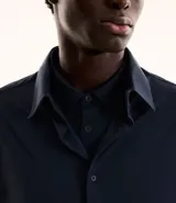 Camisa masculina de manga larga con cuello inglés y cierre frontal abotonado. Confeccionada en tejido de poliamida con tecnología performance, que ofrece elasticidad, secado rápido y resistencia a las arrugas.