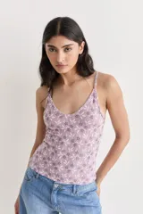 Musculosa de encaje color lila con estampado de flores blancas y grises, de breteles finos y corte ajustado.