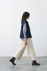 Chaleco de jean en tono celeste claro, con corte recto, cuello camisero, cierre frontal con botones metálicos y costuras visibles.