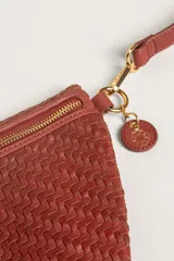 Bandolera de gamuza color marrón con diseño de media luna, decorada con tachas metálicas doradas distribuidas en el frente. Cuenta con cierre superior metálico y correa larga ajustable para llevar cruzada.