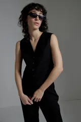 Chaleco negro de corte sastrero con escote en V y cierre frontal con botones.
